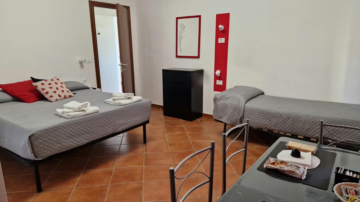 Camera Coccinella: letto matrimoniale, letto singolo, cassettiera e tavolo con la colazione